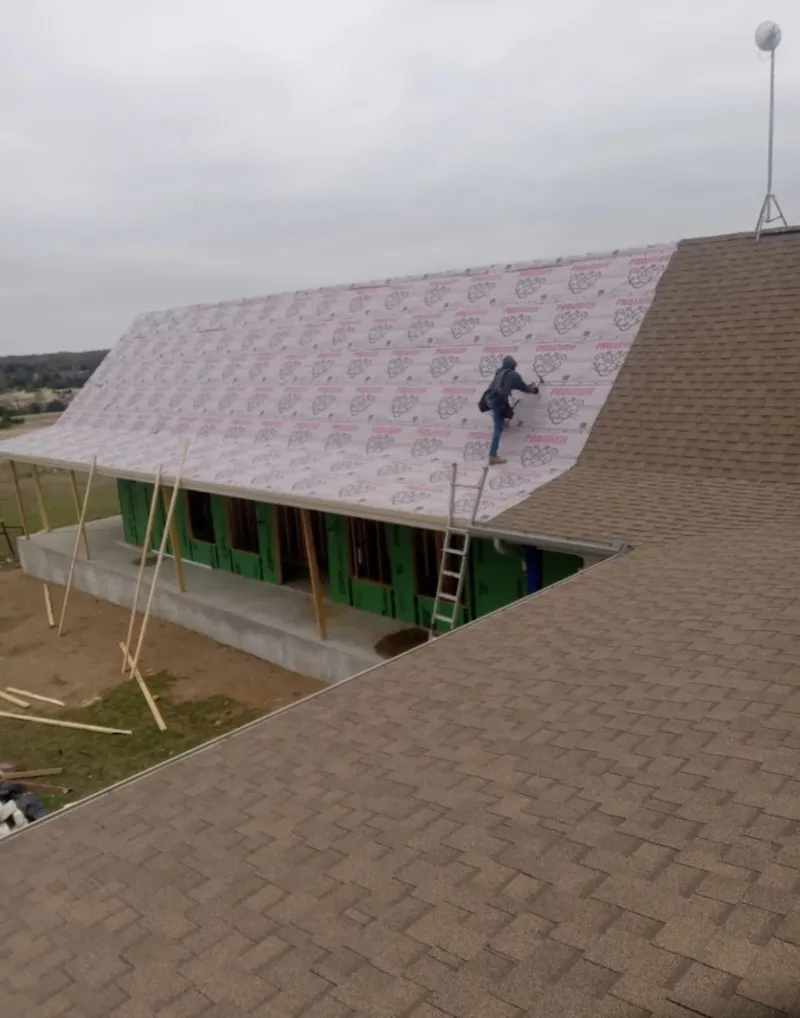 Worker preparing underlayment for a metal roof installation in Amelia